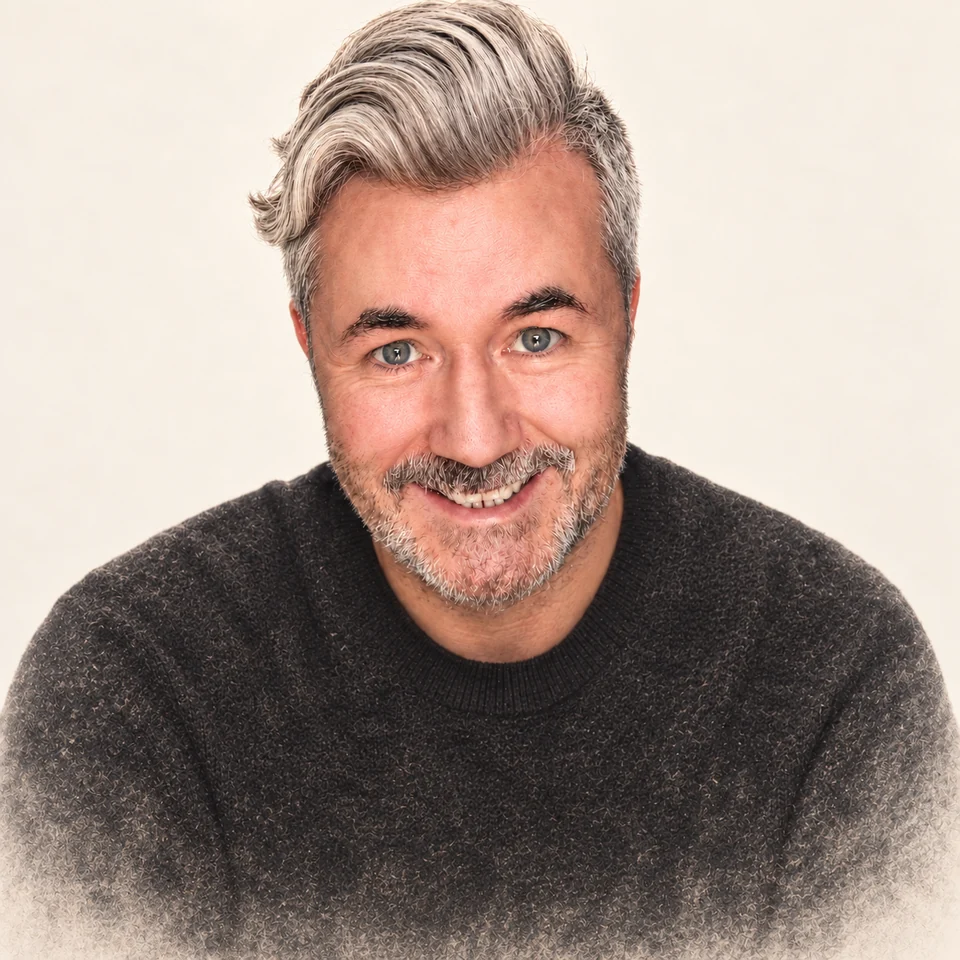 Paul McGlade smiling, with silver hair and a beard, against a warm cream background