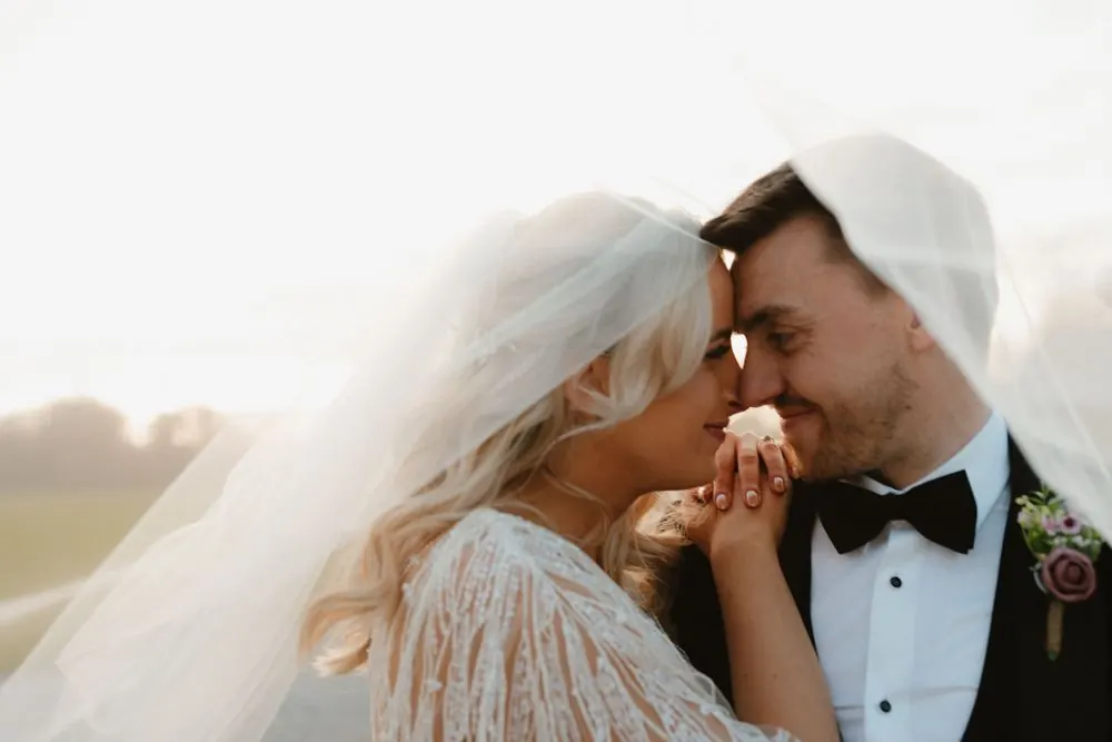 Bride and groom sharing a romantic kiss at golden hour, with flowing veil and classic black tuxedo Boyne Hill House Estate, Co. Meath