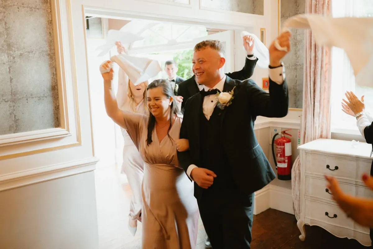 The couple raising their arms as they enter the reception