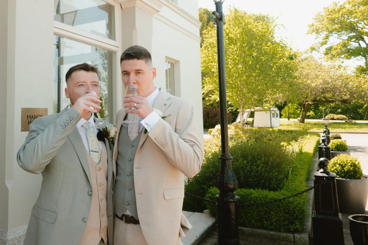The grooms raising their glasses outside the house