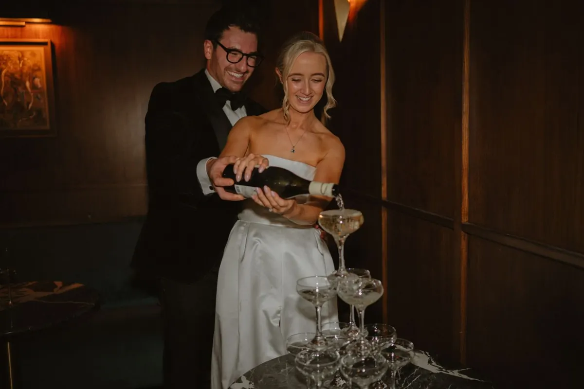 The couple pouring drinks into a tower of glasses