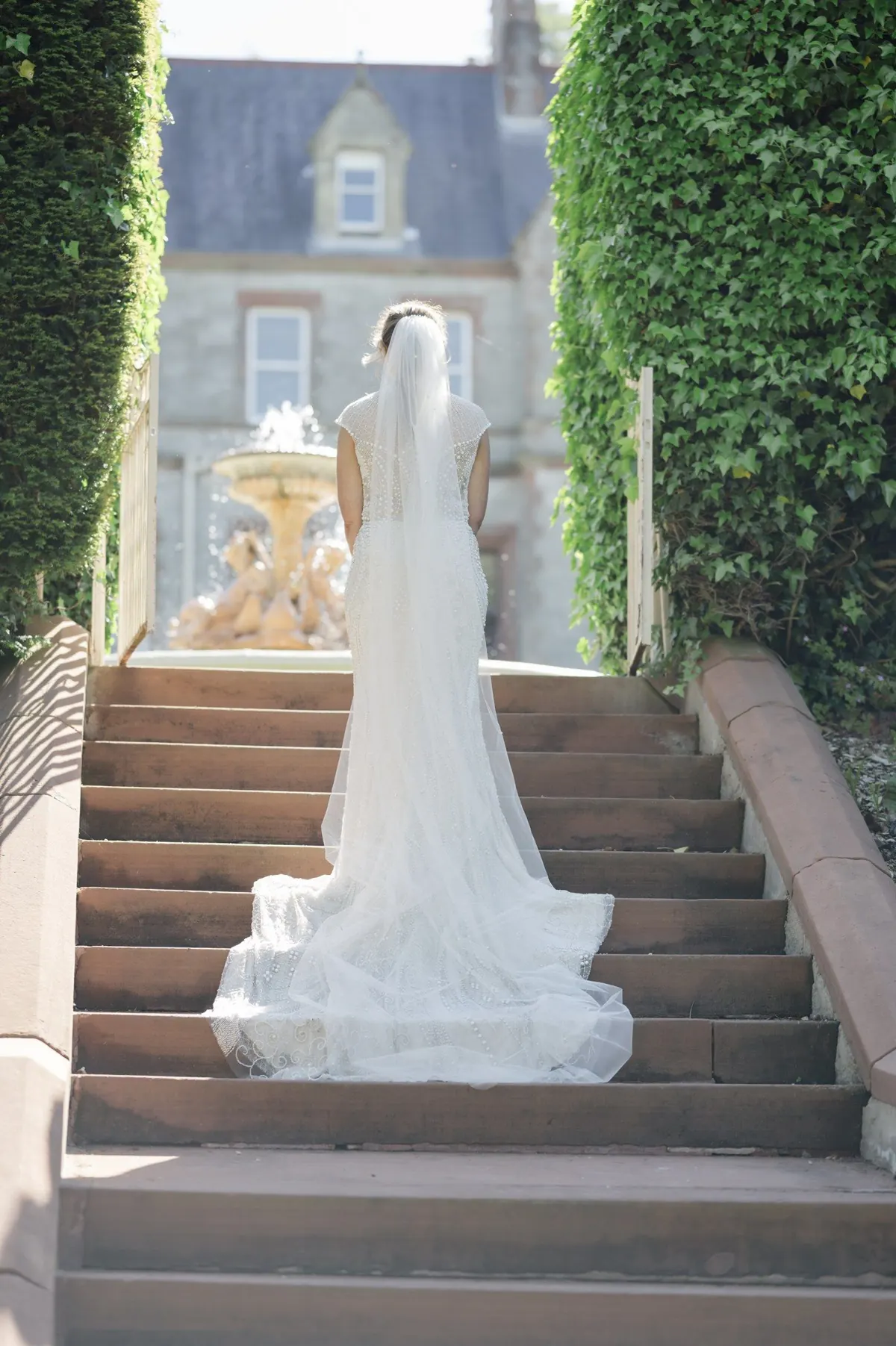 Steph on the stone steps between clipped hedges