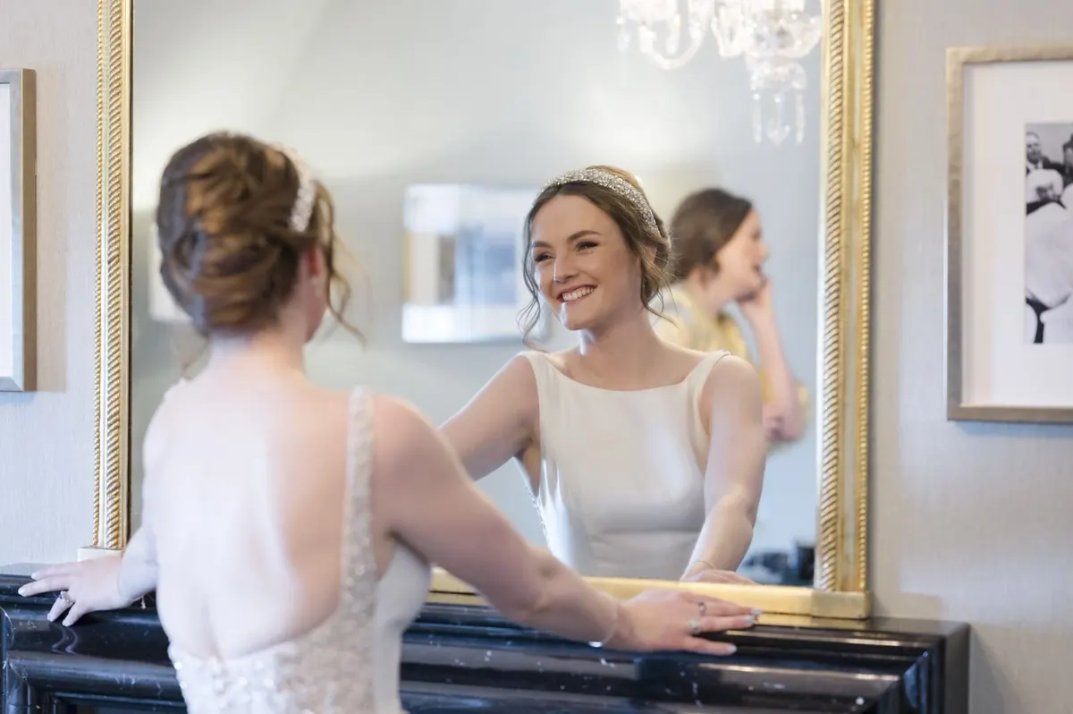 Carole and a bridesmaid sharing a moment beside the mirror.