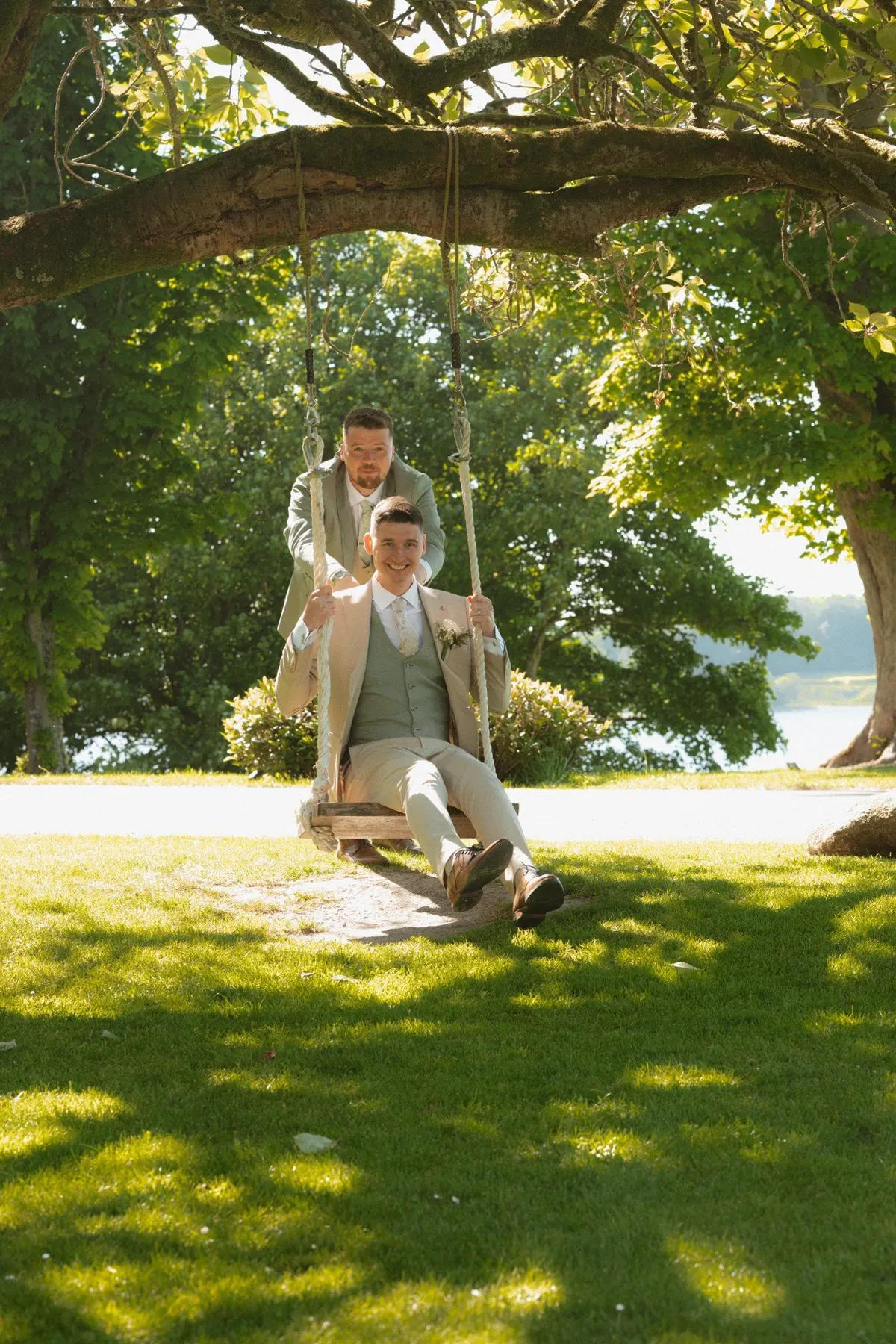 The grooms seated together beneath a broad tree