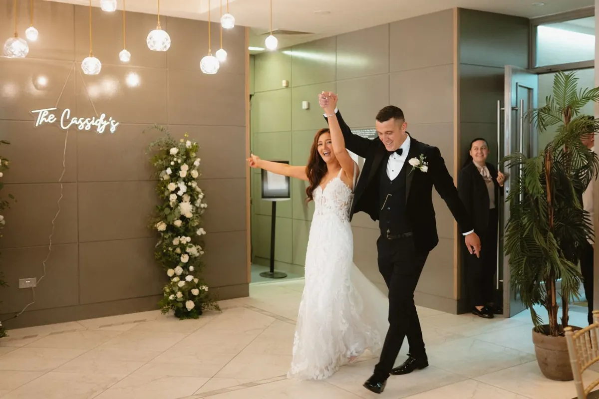 The couple raising their joined hands as they arrive at the reception