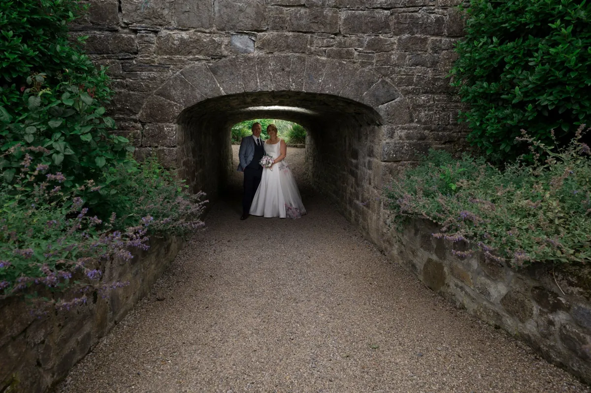 Bride and groom framed by a stone garden passage at Clonabreany House.