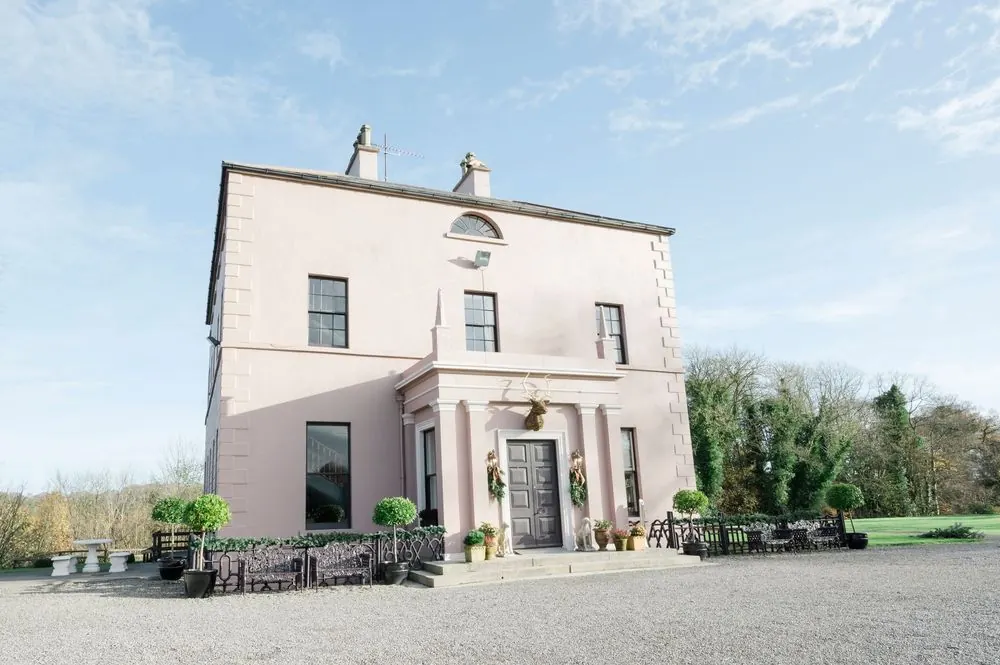 Boyne Hill House is a Georgian country house with ornate iron railings, topiary trees, and gravel driveway surrounded by mature trees.
