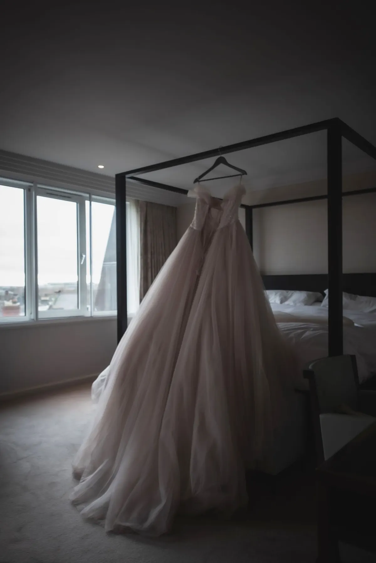 The wedding dress hanging beside the hotel-room window