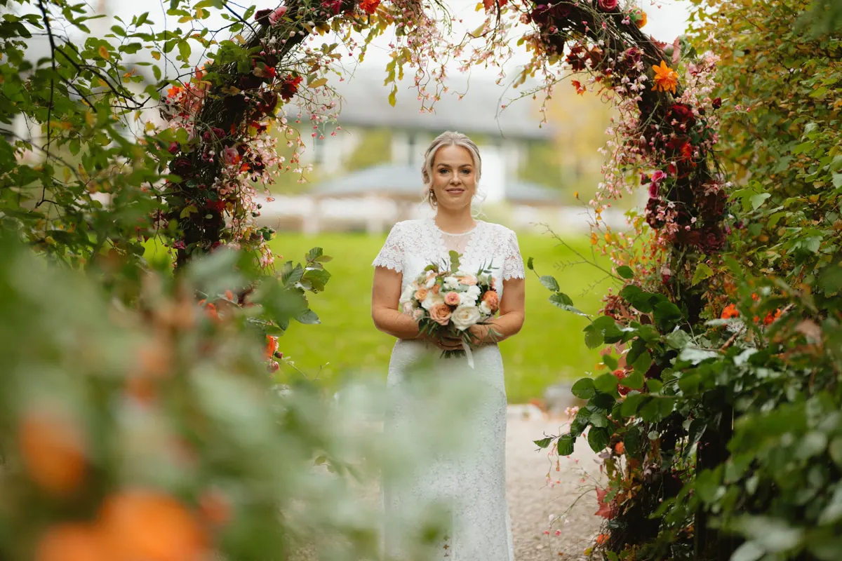 Bride beneath a flower-covered arch in the gardens at BrookLodge.