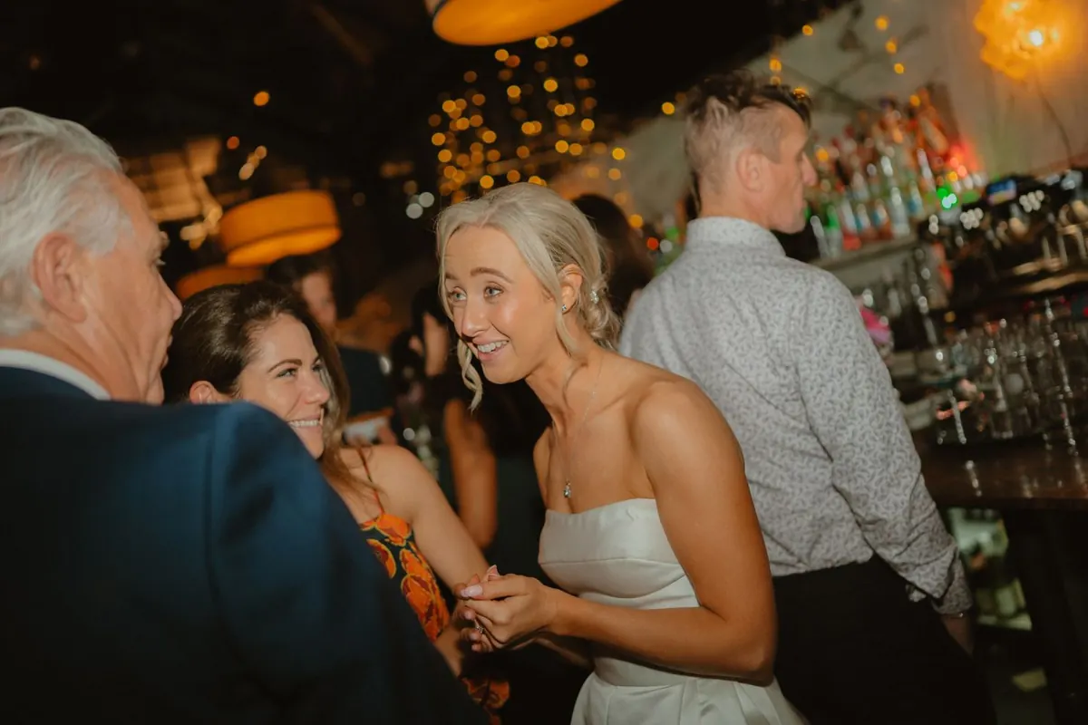 The bride laughing with guests beside the bar