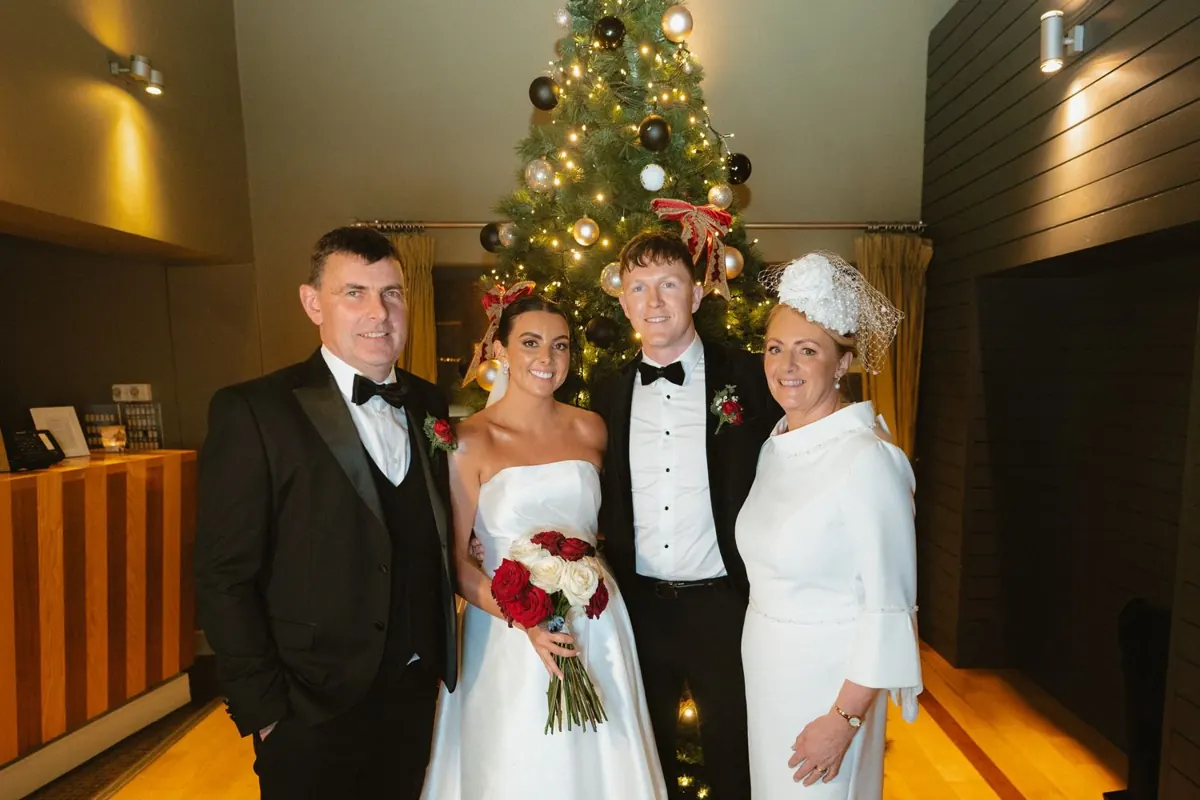 The couple with guests beside a decorated Christmas tree