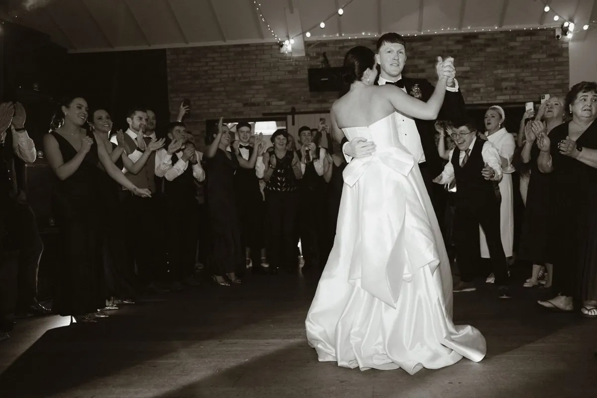 Black and white view of the couple’s first dance surrounded by guests