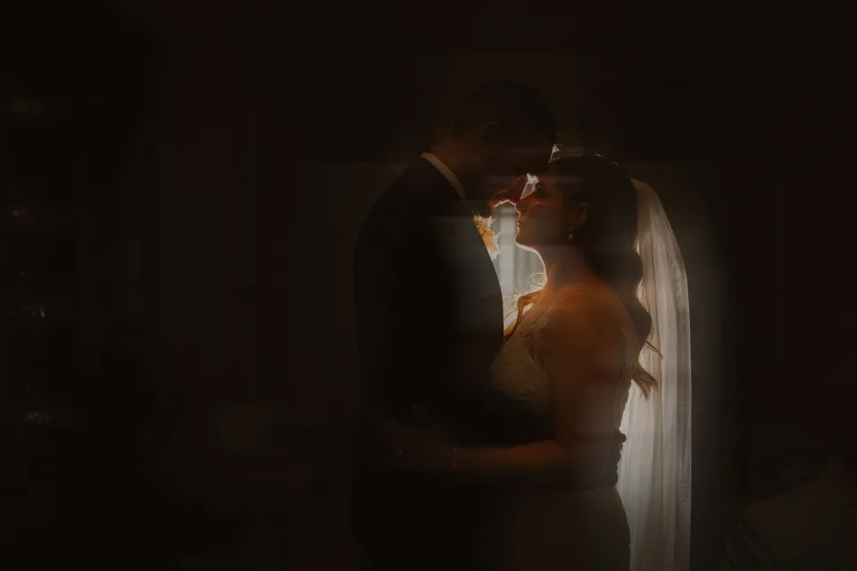 A bride and groom share a romantic moment in soft backlight, silhouetted in an intimate wedding portrait at Tankardstown House, Co.Meath