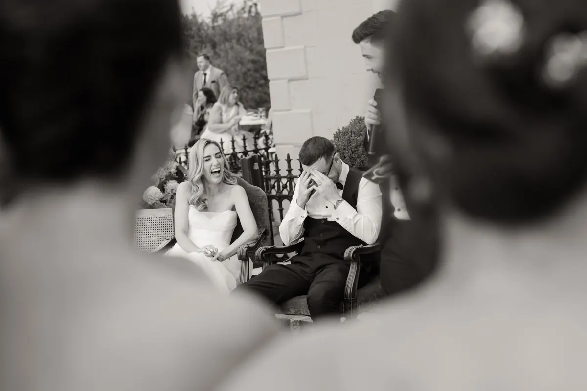 Wedding photo of bride and groom seated outdoors, groom wiping tears during emotional speeches moment at Boyne Hill House Co. Meath
