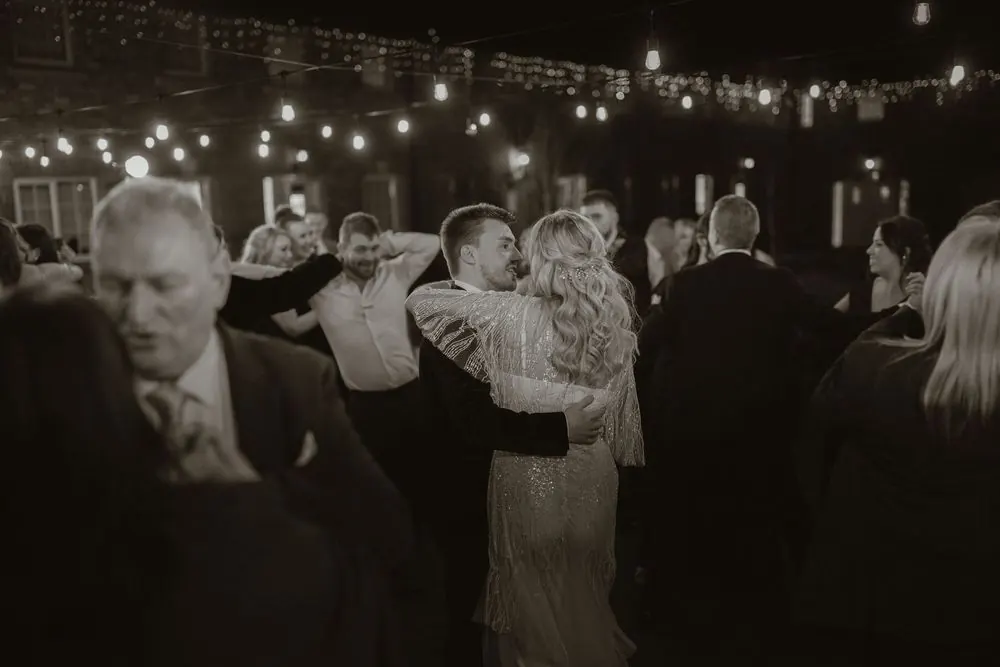 Couple shares romantic first dance under string lights at elegant evening wedding reception at Boyne Hill House Estate, Co. Meath