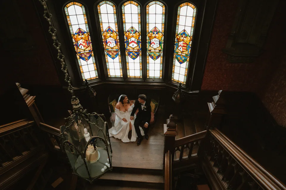 Brooke and David beneath the stained-glass staircase windows