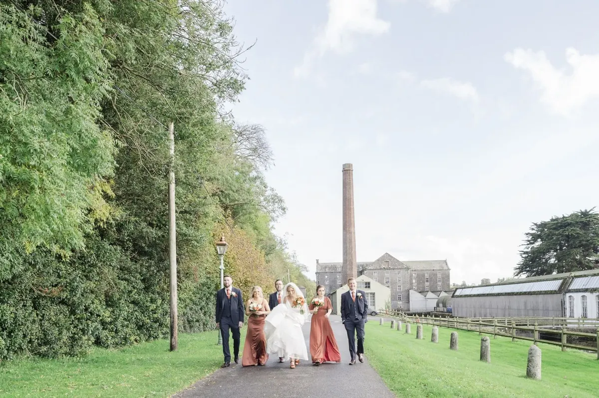 The wedding party walking through the grounds near the old mill