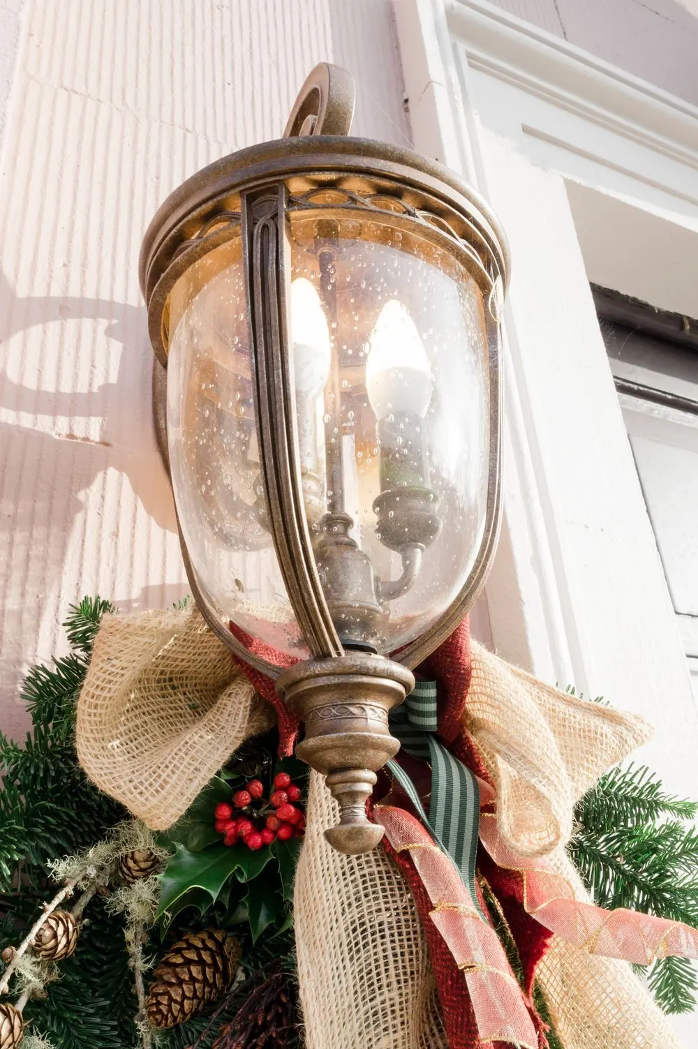 Boyne Hill House vintage brass outdoor lantern decorated with burlap bow, holly berries, and evergreen branches for Christmas.