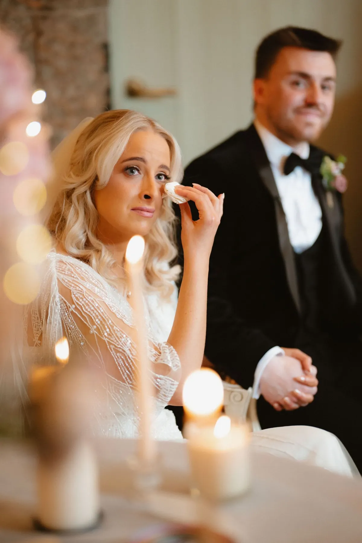 Emotional bride wiping tears at wedding ceremony at Boyne Hill House Estate, Co. Meath, surrounded by candlelight.