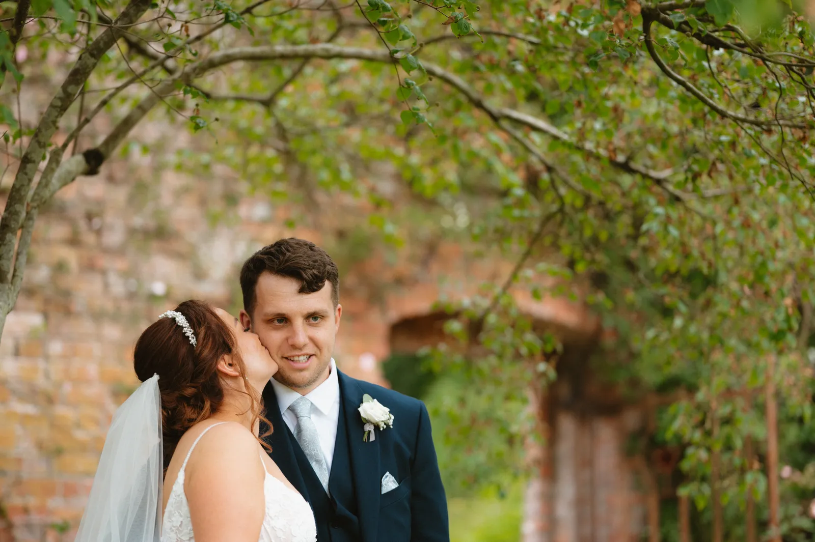 Claire and Will beneath a leafy brick garden arch at Ballyscullion Park