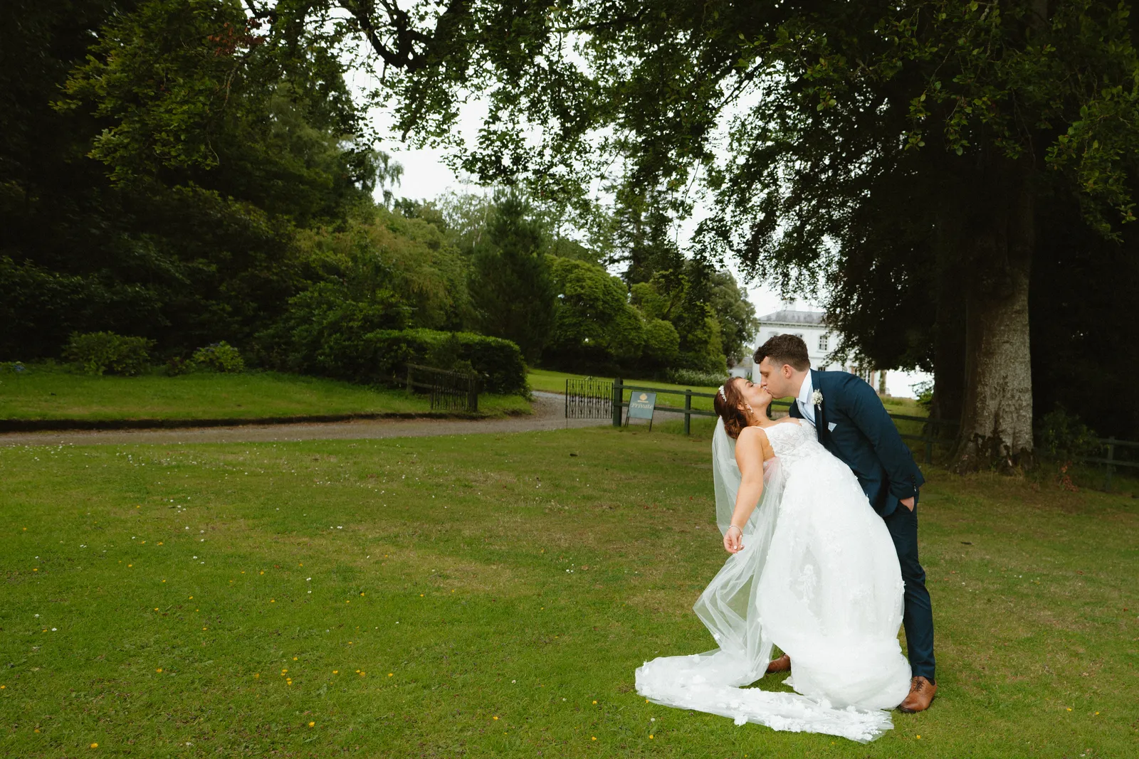 Will dips Claire for a kiss on the lawn beneath a broad tree.