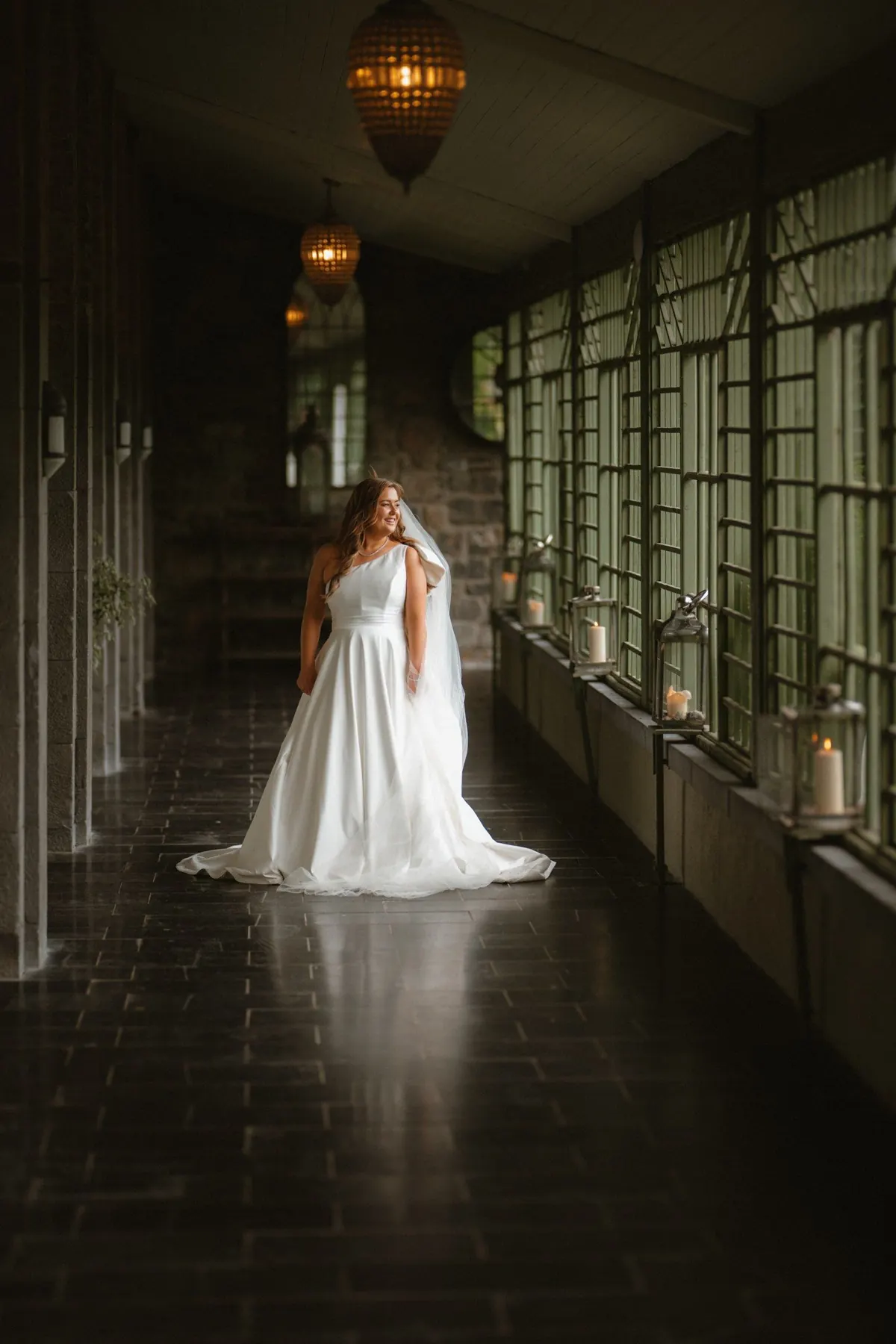 The bride in a long corridor beside tall windows