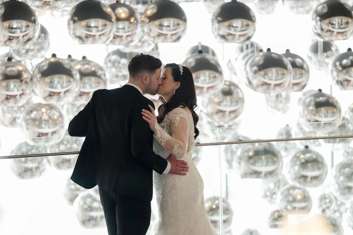 Michelle and Chris kissing in front of the reflective installation at The G Hotel.
