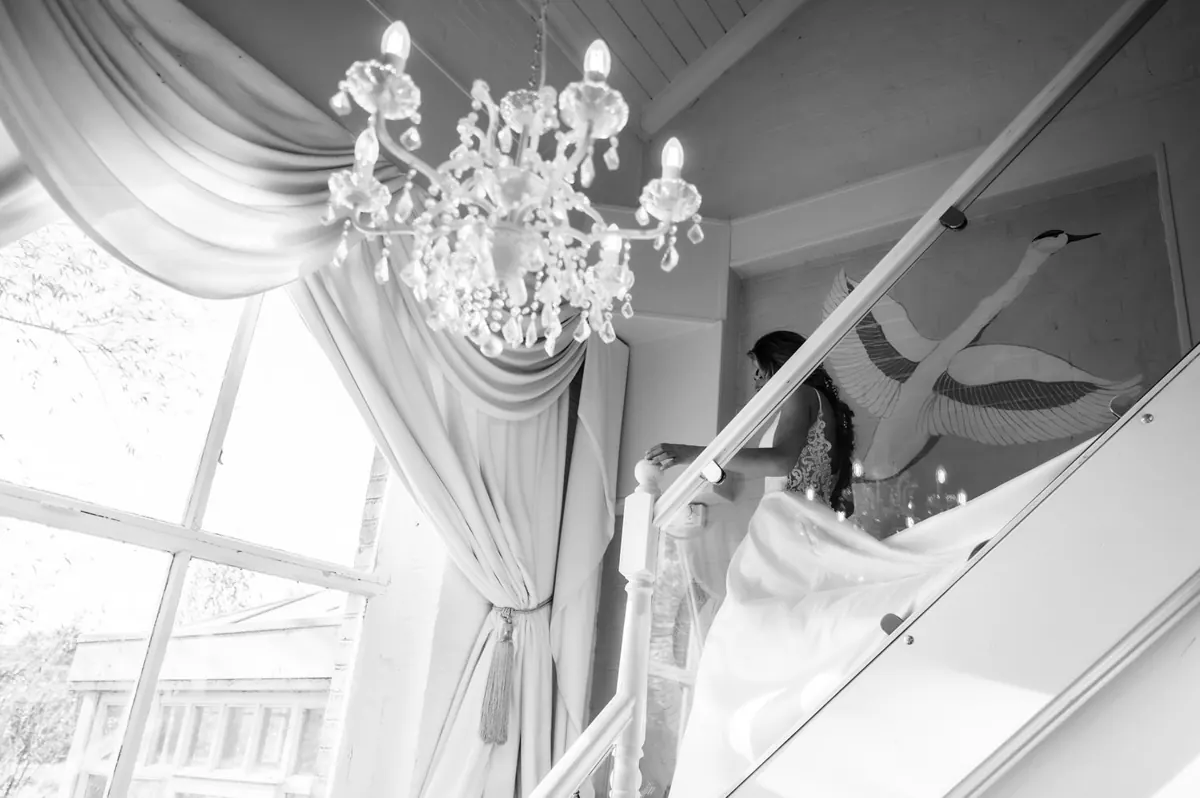 A black-and-white view of the bride on the bright staircase