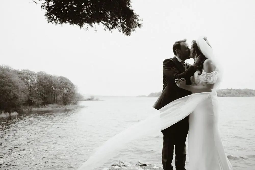 Aine and John embracing by the lakeshore.