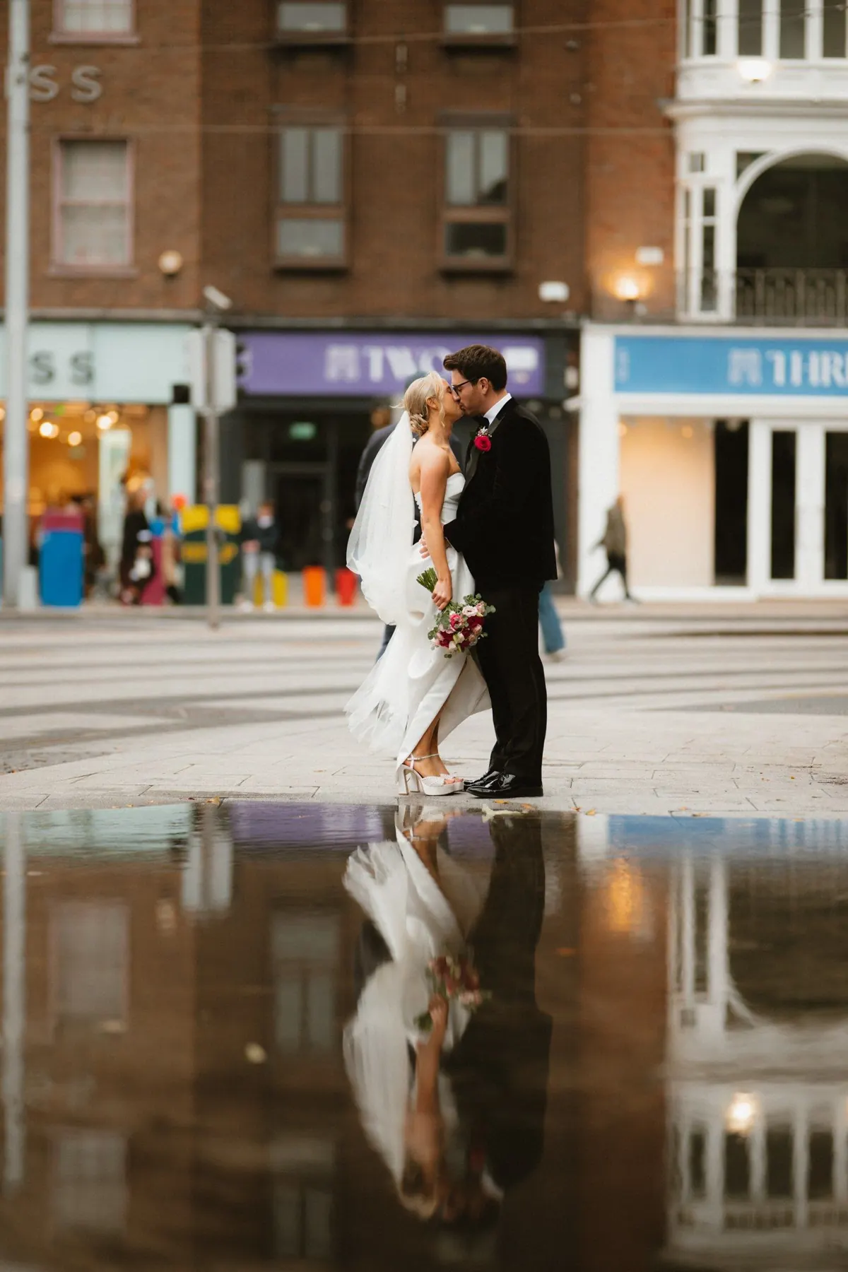 The couple reflected in a puddle on a city street