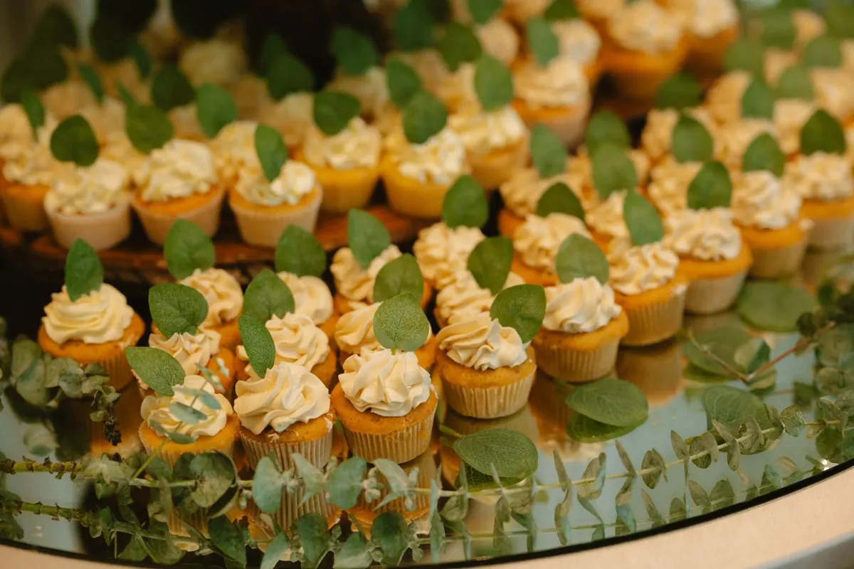 A display of small iced cupcakes topped with green leaves