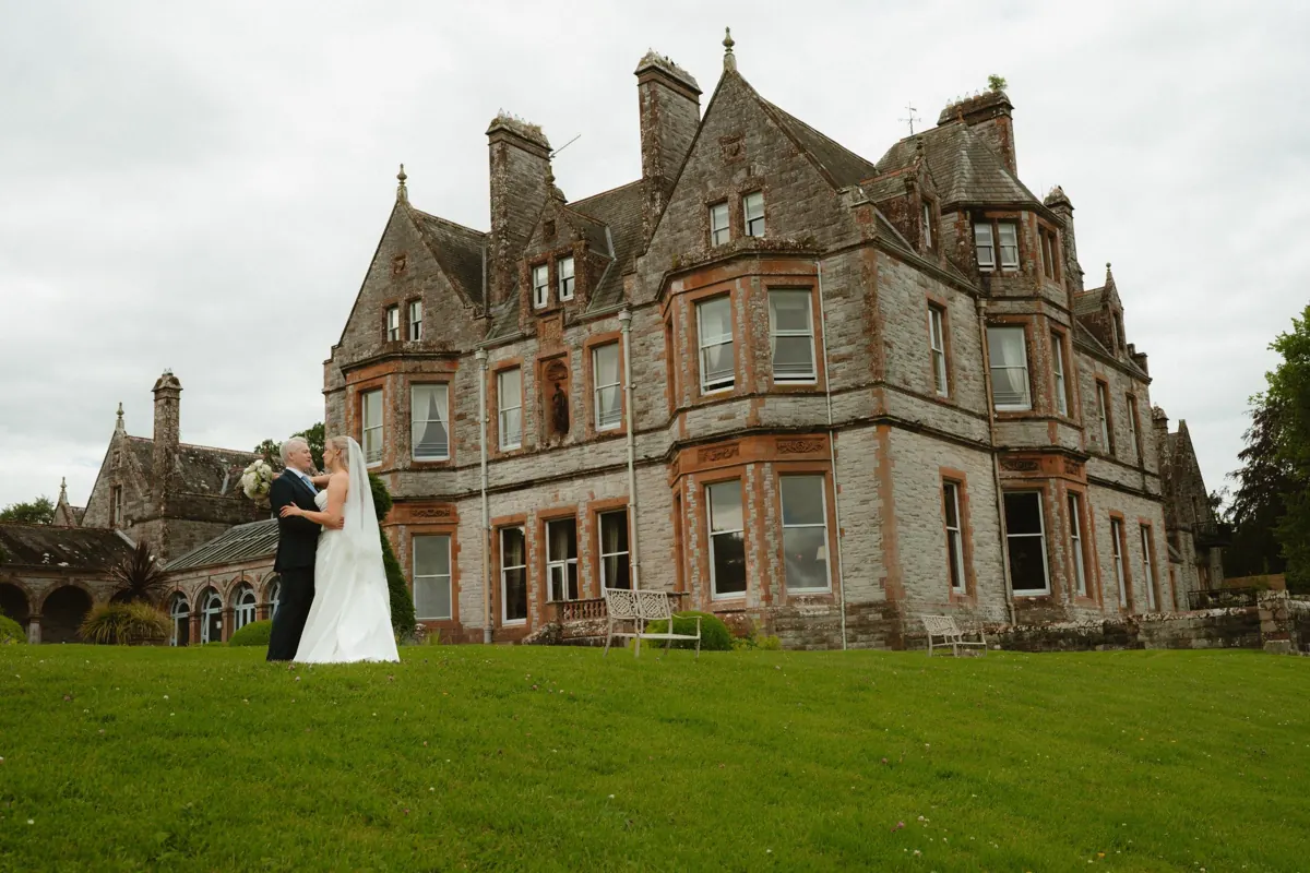 Bride and groom beside the historic castle facade at Castle Leslie Estate.
