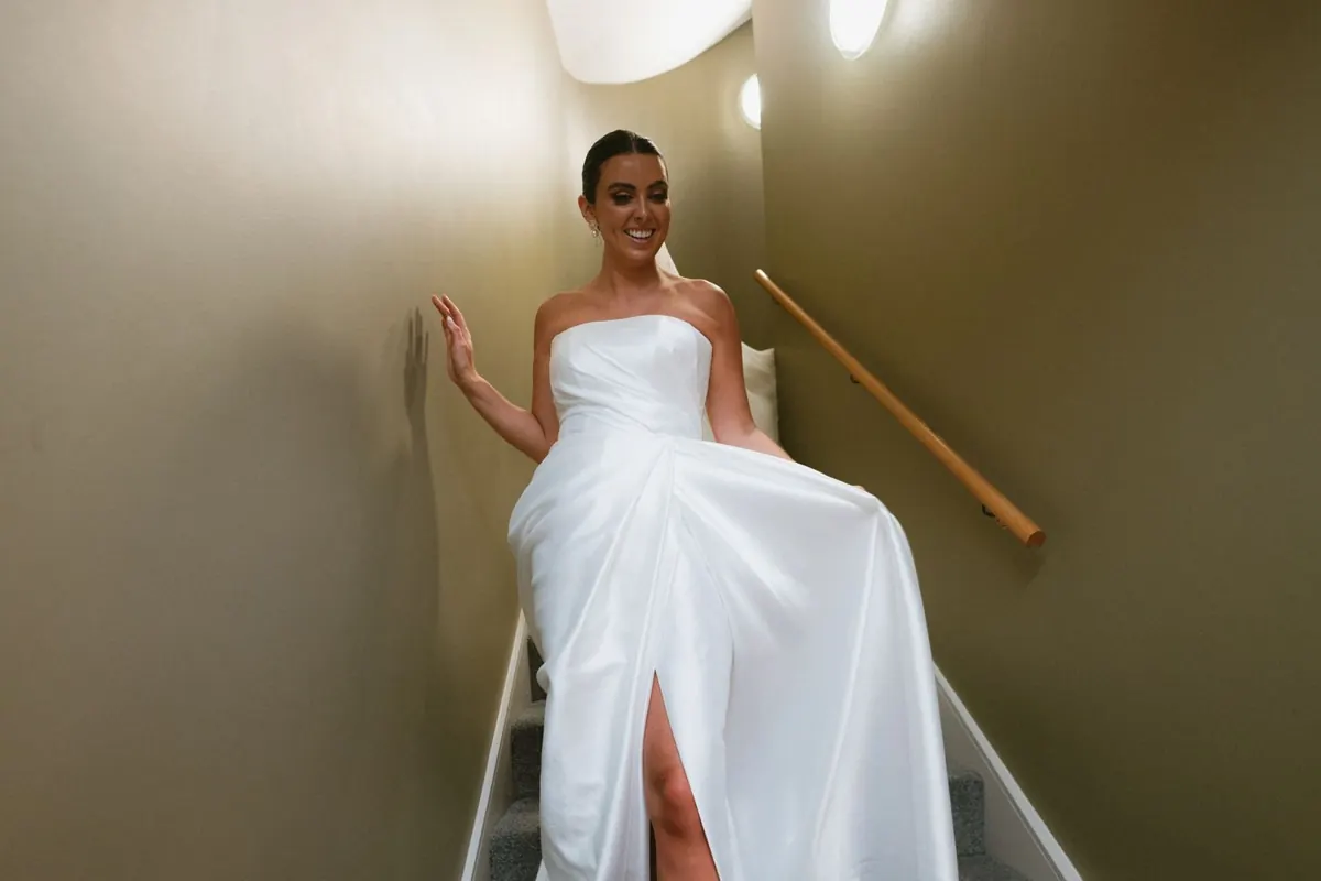 The bride lifting her skirt as she comes down the stairs
