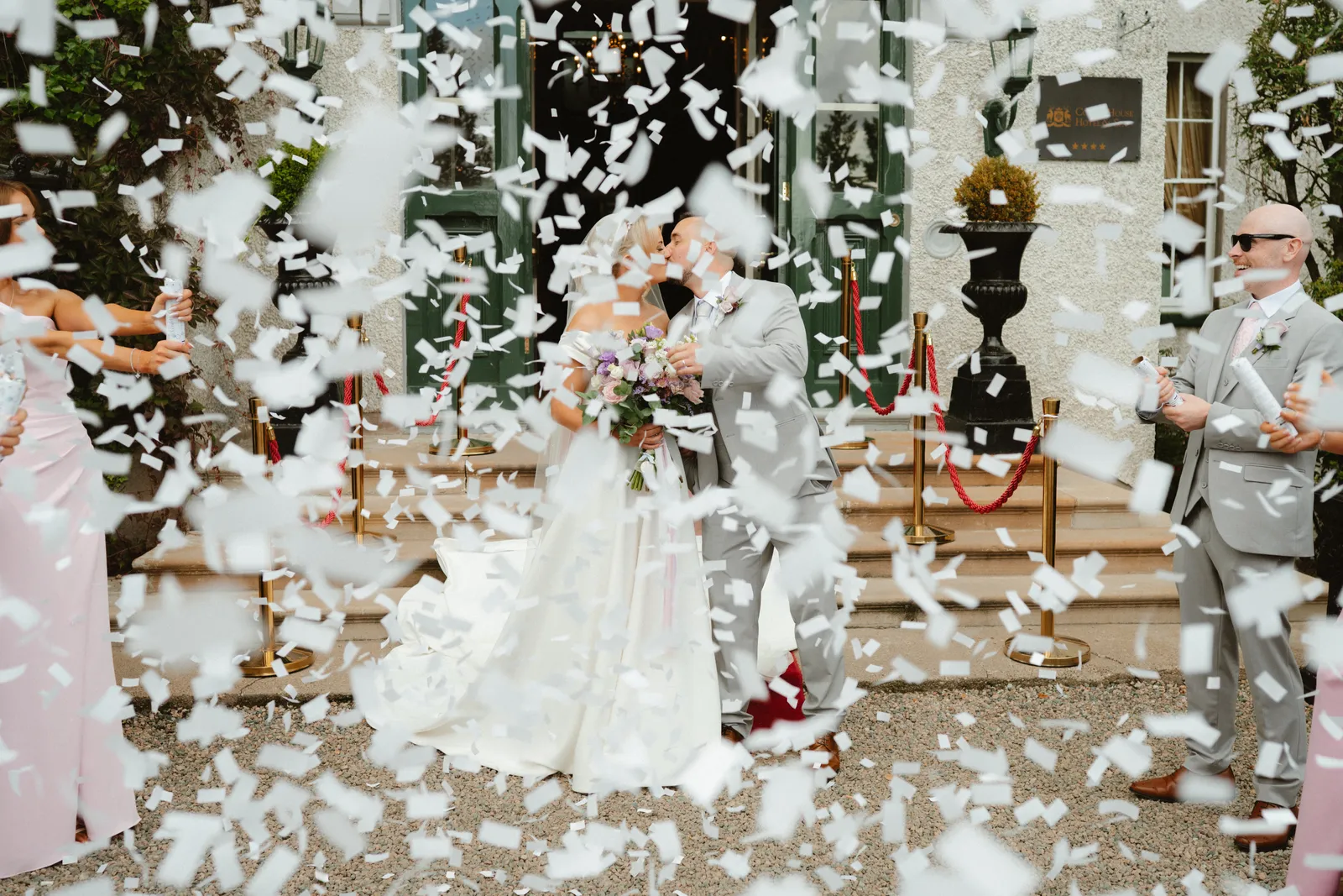 Emma and Kevin emerge through a shower of confetti outside Corick House.