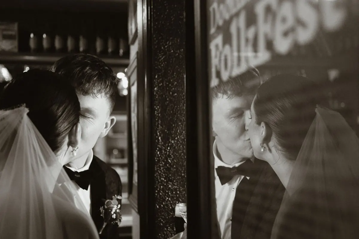 Black and white reflection of the couple beside a sign at the bar