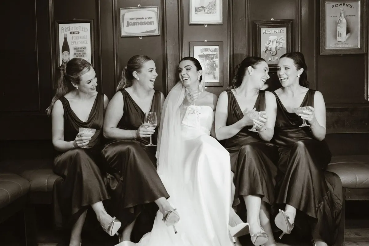 Black and white photograph of the bride seated with women in matching dresses