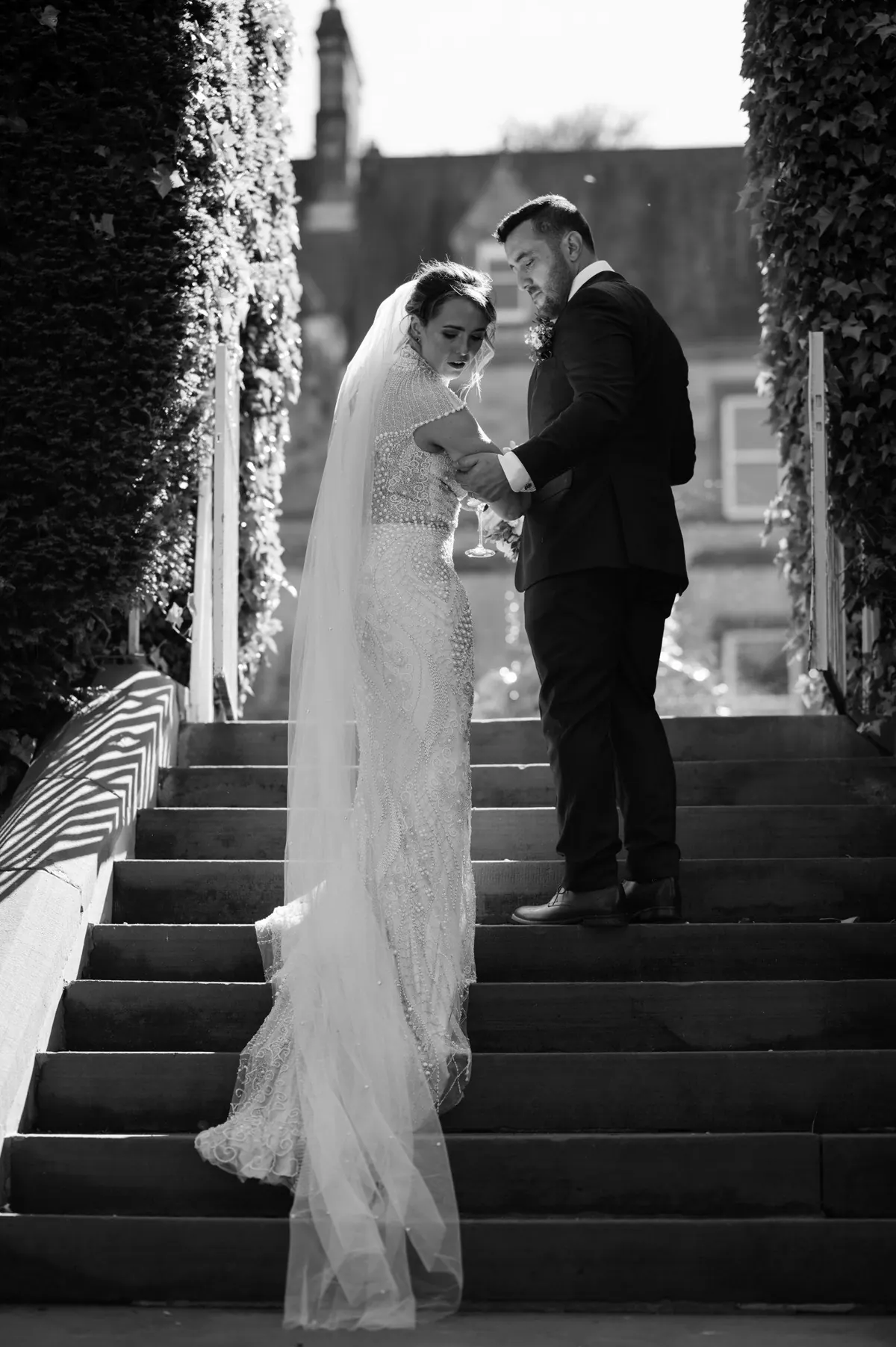 A black-and-white portrait of the couple on the estate steps