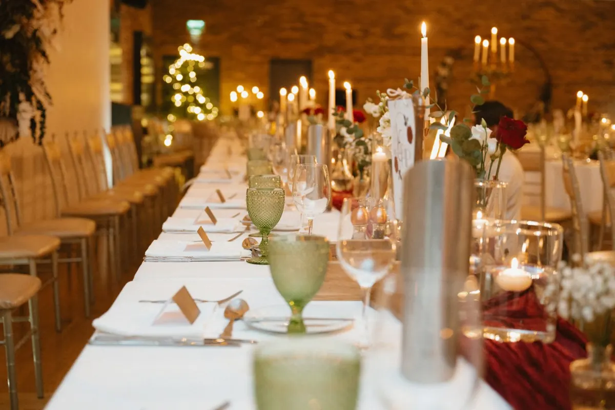 Reception tables set with candles, glassware and red napkins