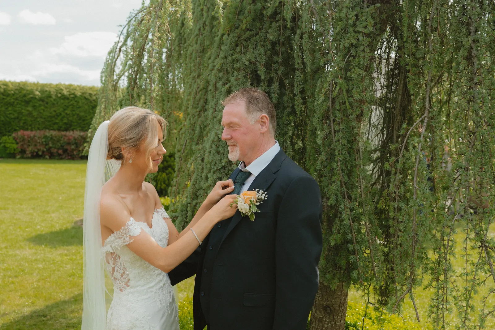 Hazel adjusting Luke’s tie beside the willow