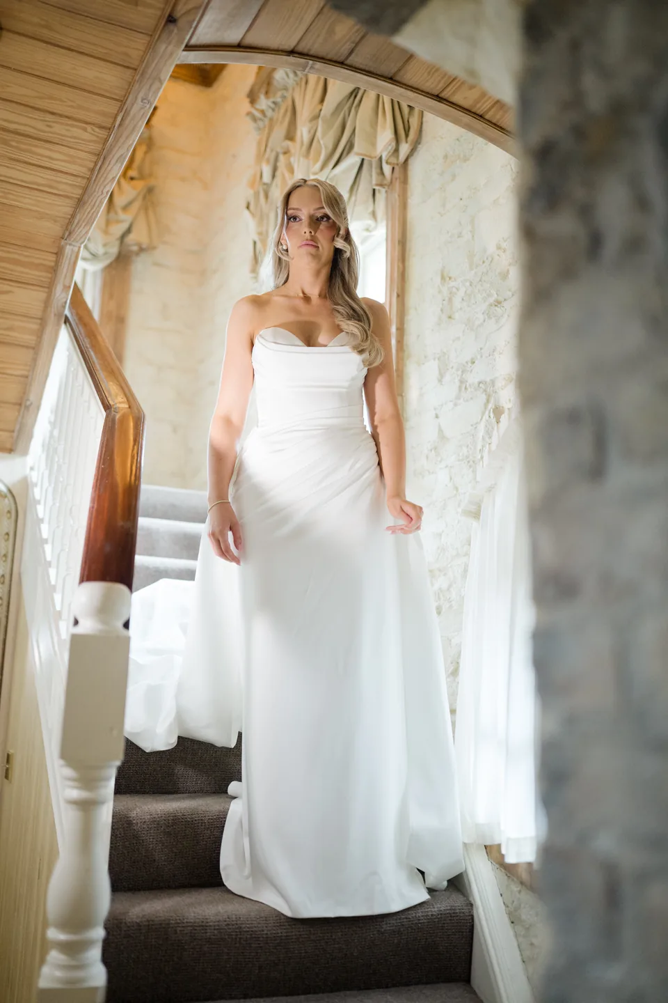 Holly in her wedding dress framed by a stone doorway.