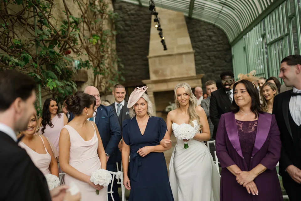 Holly walks into the ceremony, framed by seated guests.