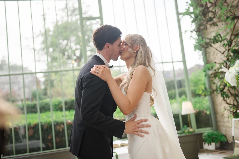 The ceremony kiss in the light-filled conservatory.