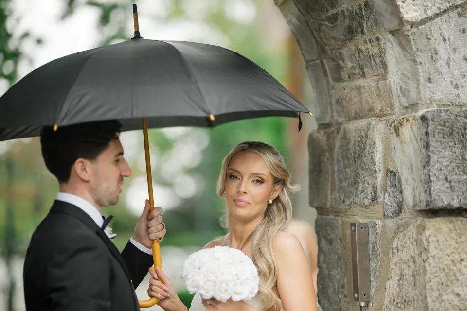 A close umbrella portrait with the stone wall and green background.