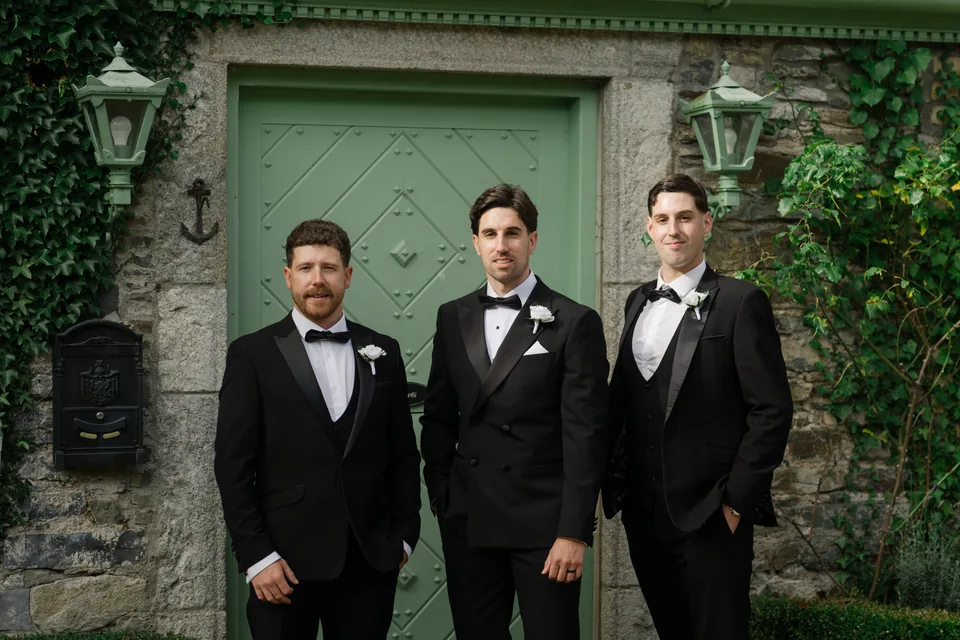 Groom and groomsmen framed by the green doorway.