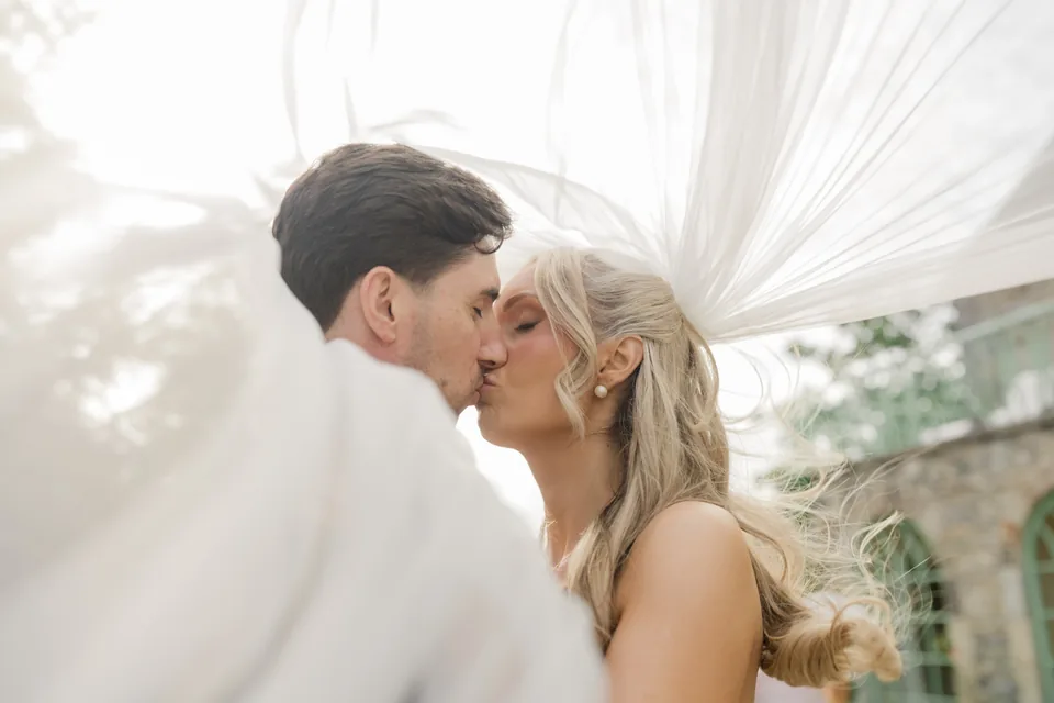 A kiss under the veil with airy light and close framing.