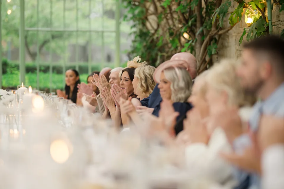 Guests applaud together along the long table.