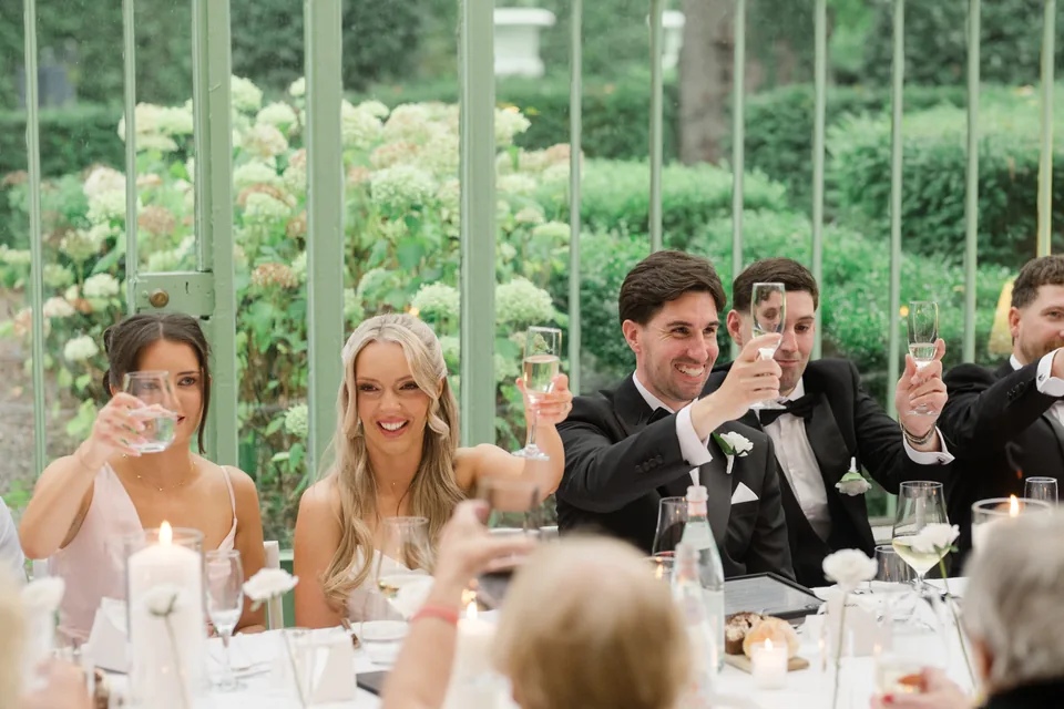 The couple and bridal party laugh during a speech.