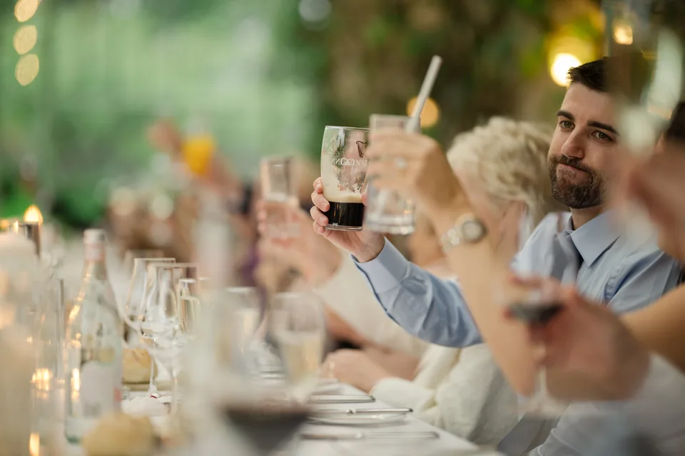Guests raise their glasses in a close toast detail.