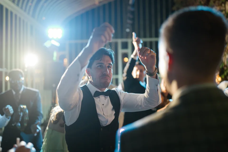 Guests with raised arms and colourful backlight on the dance floor.