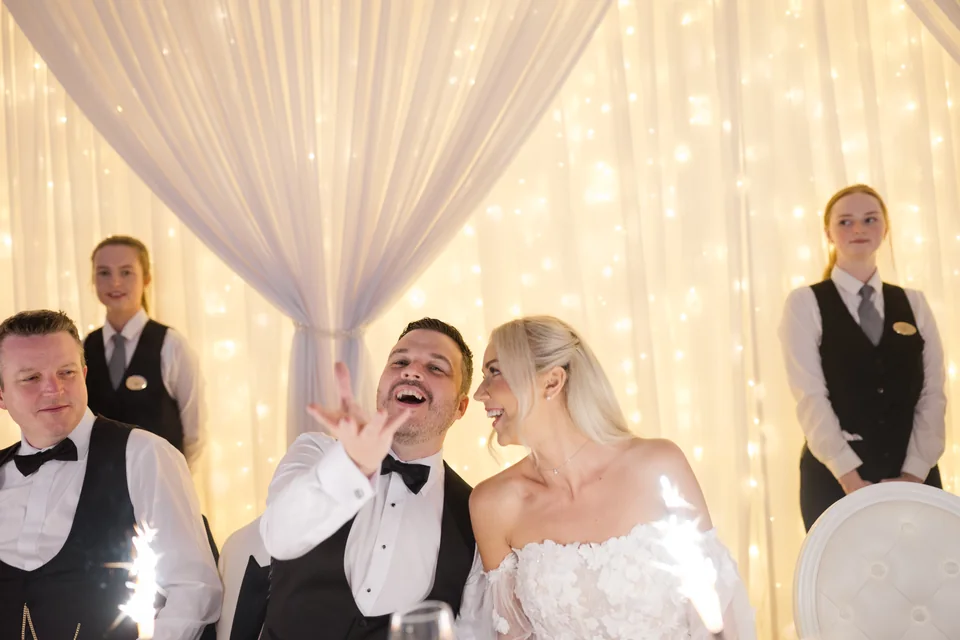 Ieva and Darren laughing as dessert arrives at their reception